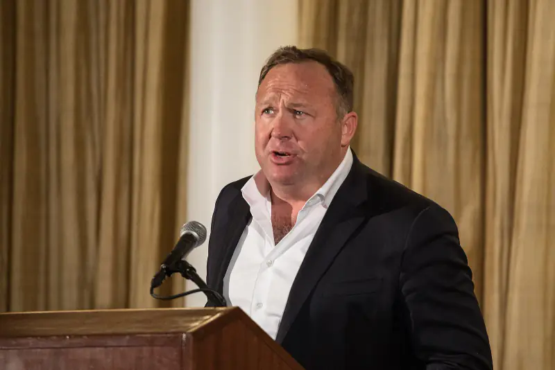 Alex Jones speaking at a wooden podium at a press conference in Washington, D.C., April 2018