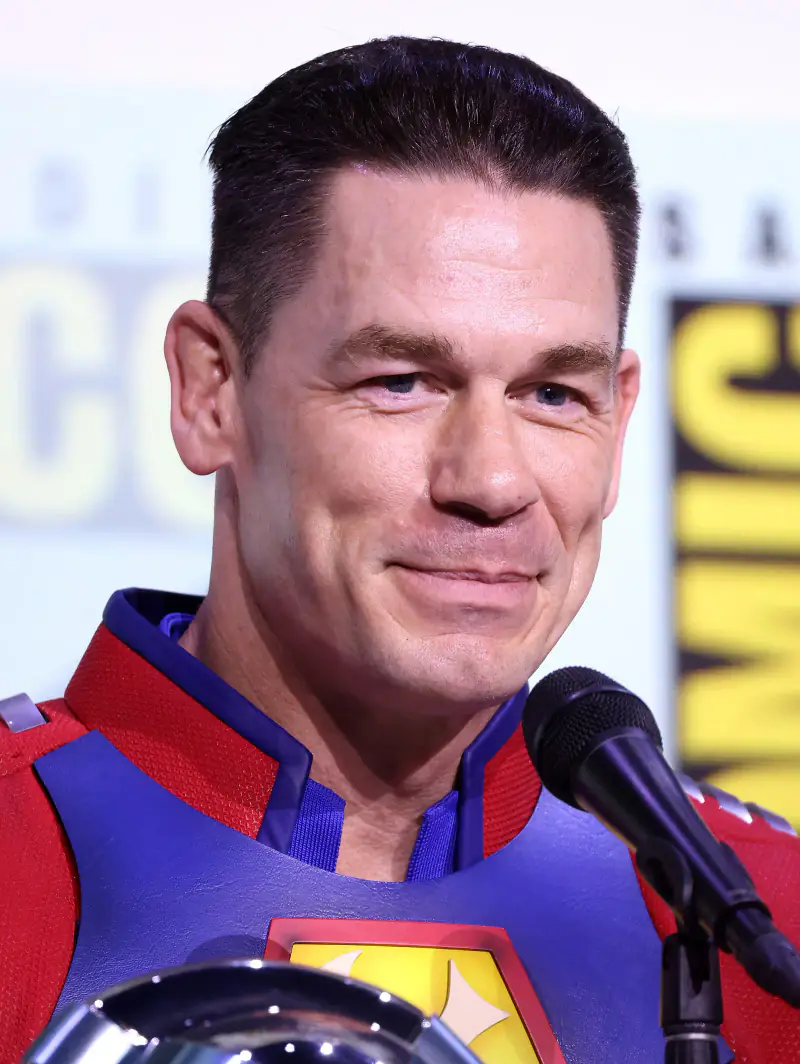 John Cena smiling in his Peacemaker costume on a San Diego Comic-Con panel, July 2025