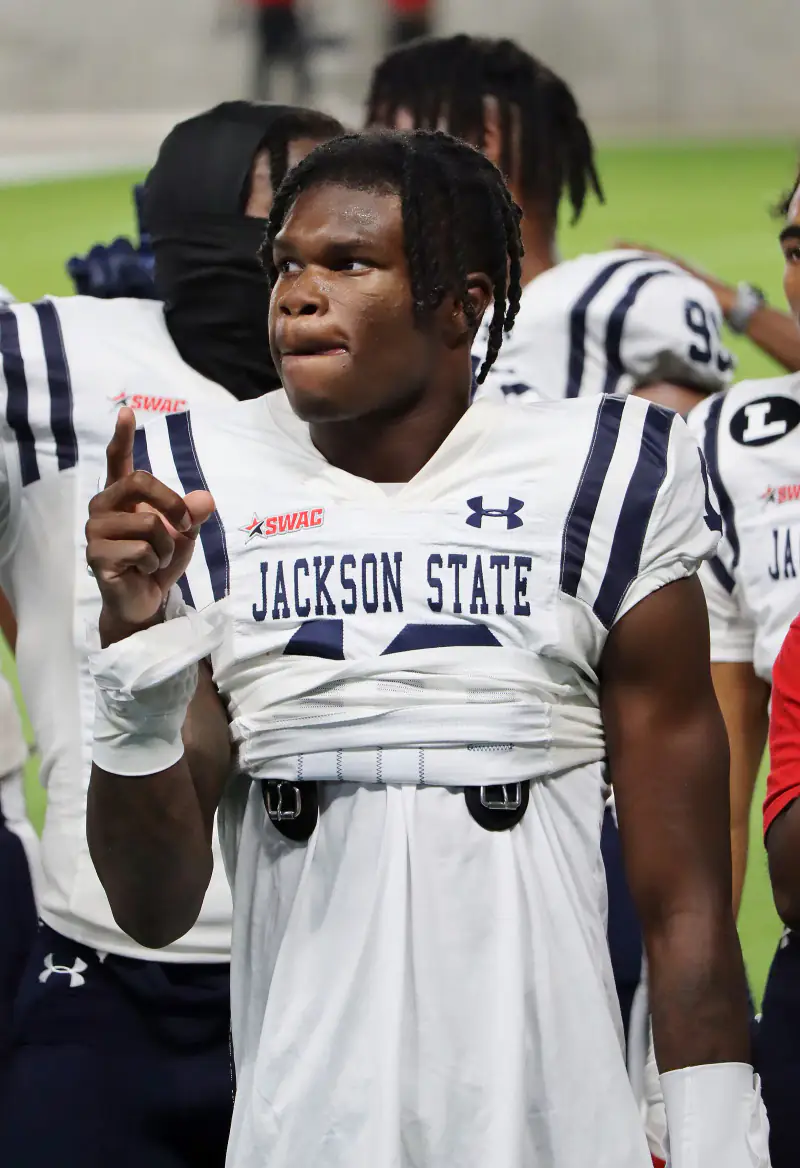 Travis Hunter in a white Jackson State uniform raising one finger on the sideline during a 2022 game against Texas Southern